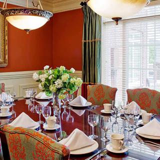 An elegantly set dining room with a floral centerpiece and a chandelier.