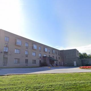 A three-story residential building with a grassy lawn and clear blue sky.