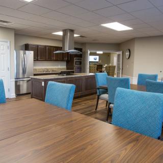 A modern kitchen and dining area with blue chairs and wooden tables.