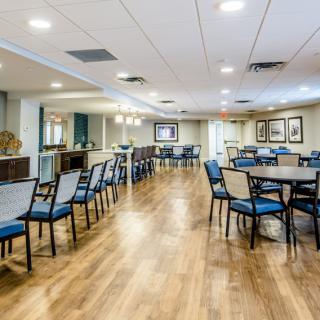 A spacious dining room featuring multiple tables and chairs on a hardwood floor, with bright lighting and modern interior design.