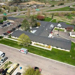 Aerial view of a residential building with surrounding greenery and parking area.