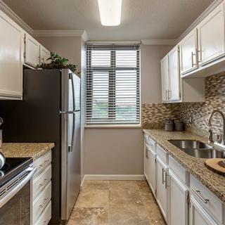 A modern kitchen with white cabinets and a stainless steel refrigerator.
