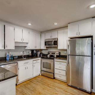 Modern kitchen with white cabinets and stainless steel appliances.