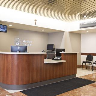 A modern reception area with a wooden desk and waiting chairs.