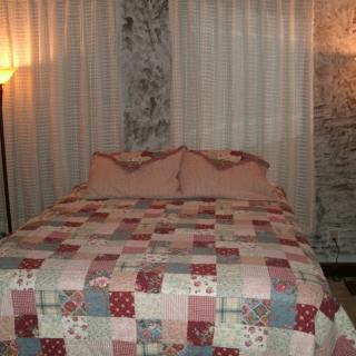 A cozy bedroom featuring a bed with a patchwork quilt and soft lighting.