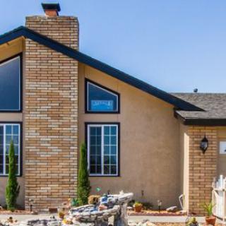 A modern house featuring large windows and a prominent brick chimney.