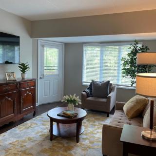 A cozy living room with a comfortable seating area, a television, and natural lighting from a large window.