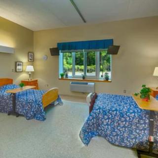 A hospital room with two patient beds and a window view.