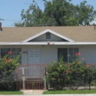 A small residential house with a front garden and bushes.