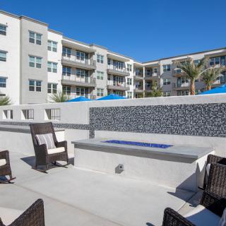 A modern apartment complex featuring an outdoor patio area with comfortable seating and a fire pit.