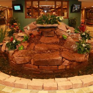 An indoor fountain with a rock garden and surrounding plants, located in a hotel lobby.
