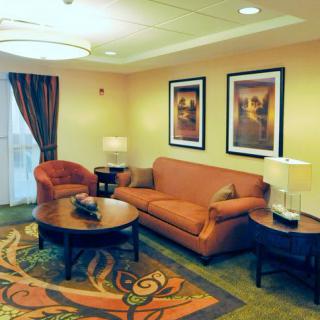 A cozy living room with a sofa, armchair, and coffee table, complemented by wall art and warm lighting.