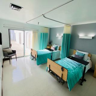 A modern hospital patient room designed for comfort and functionality, featuring two beds and natural light.
