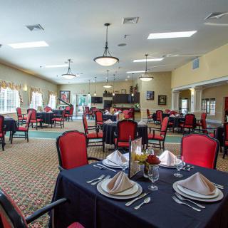 An elegant dining room with neatly arranged tables and red-accented chairs.