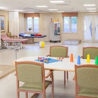 A well-lit rehabilitation room equipped with therapy tools and furniture.