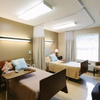 A hospital room with two beds, separated by curtains, in a healthcare facility.