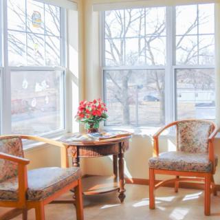 A cozy sunlit corner with two chairs and a table holding a flower arrangement.