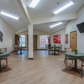 A spacious dining area with multiple tables and chairs, featuring decorative art on the walls.