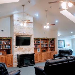 A cozy living room with a fireplace, built-in bookshelves, and a television, featuring comfortable seating and ceiling fans.