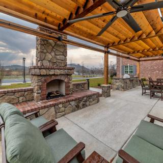 A cozy outdoor patio with a stone fireplace under a wooden pergola.