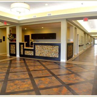 A hotel lobby area featuring a reception desk with decorative paneling and a well-lit hallway.
