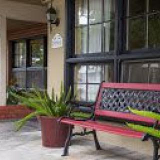 A cozy porch with a red bench and potted plants.