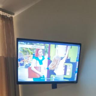 A television mounted on the wall displaying a colorful scene.