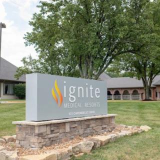 A sign labeled 'ignite' outside a building with trees in the background.