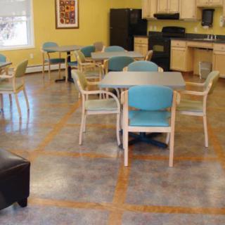 A communal kitchen and dining area with tables and chairs arranged neatly.