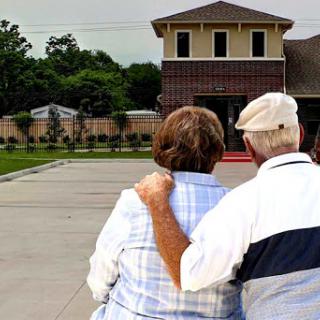 An elderly couple enjoying a moment together, looking towards their home.
