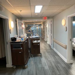 A well-lit hallway in a medical facility, featuring patient rooms and healthcare equipment.