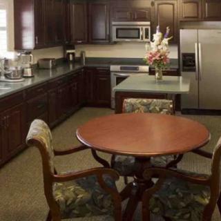 A cozy kitchen with dark wood cabinets, a small dining table, and stainless steel appliances.