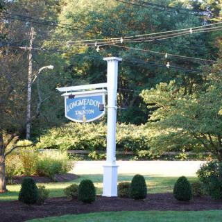 A signpost in a landscaped area with trees and shrubs in the background.