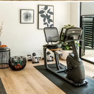 A modern home gym setup featuring a recumbent bike and various weights for indoor workouts.