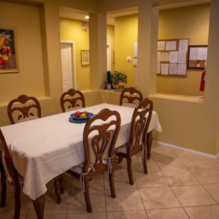 A cozy dining room with a long table and elegant chairs, surrounded by warm yellow walls.