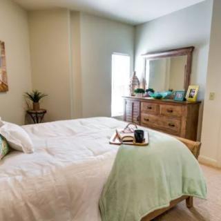 A cozy bedroom with a neatly made bed, wooden dresser, and decorative items.