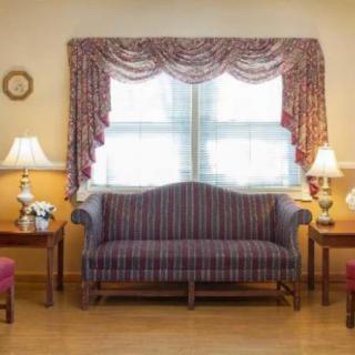 A cozy living room with a striped sofa, two lamps, and elegant curtains framing the window.