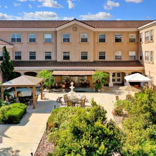 A beautifully landscaped courtyard with a fountain, surrounded by a multi-story building.