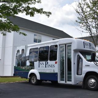 A shuttle bus parked outside a building on a sunny day.