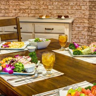 A cozy dining setting with salads and drinks arranged on a wooden table.