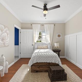 A cozy bedroom featuring a single bed, ceiling fan, and neutral decor.
