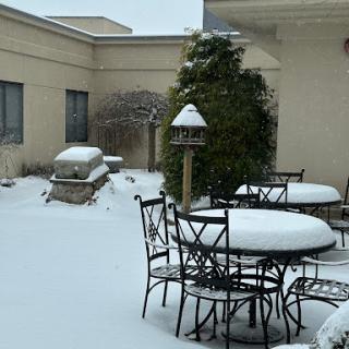 A snowy patio scene with covered furniture and a bird feeder.