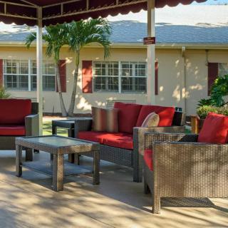 A cozy outdoor seating area with red-cushioned furniture under a gazebo, set in a garden.