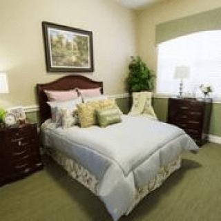 A cozy bedroom with a neatly made bed, nightstands, and decorative plants.