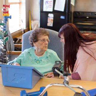 A caregiver engages in a warm conversation with an elderly resident, fostering connection and support.