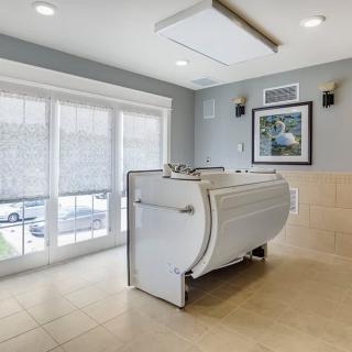 A modern bathroom featuring a walk-in bathtub with large windows and a bright, tile-floored interior.