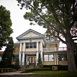 A historic building with columns and surrounding trees.