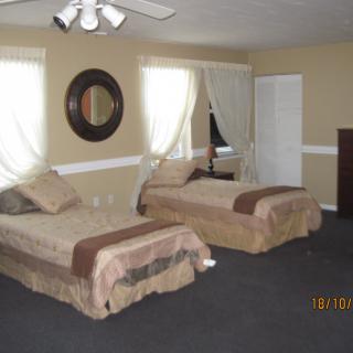 A cozy bedroom with two single beds, featuring neutral tones and a decorative wall mirror.