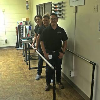 Three people creating an optical illusion in a hallway.