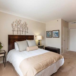 A cozy bedroom with a neatly made bed, decorative pillows, wall art, and a bedside lamp.